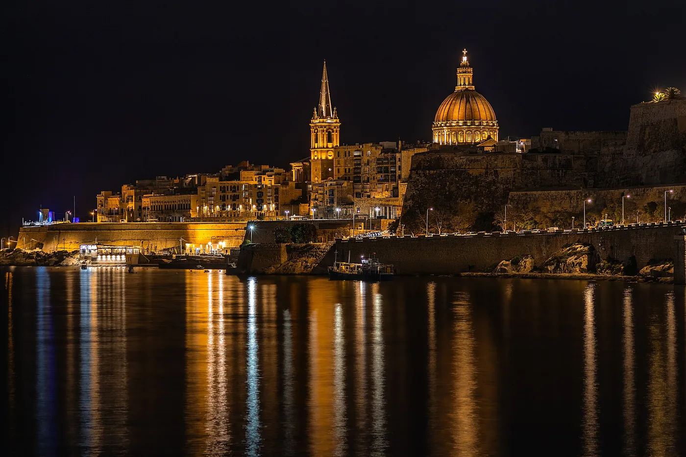 Valletta’s illuminated skyline and reflections across the harbour in Malta